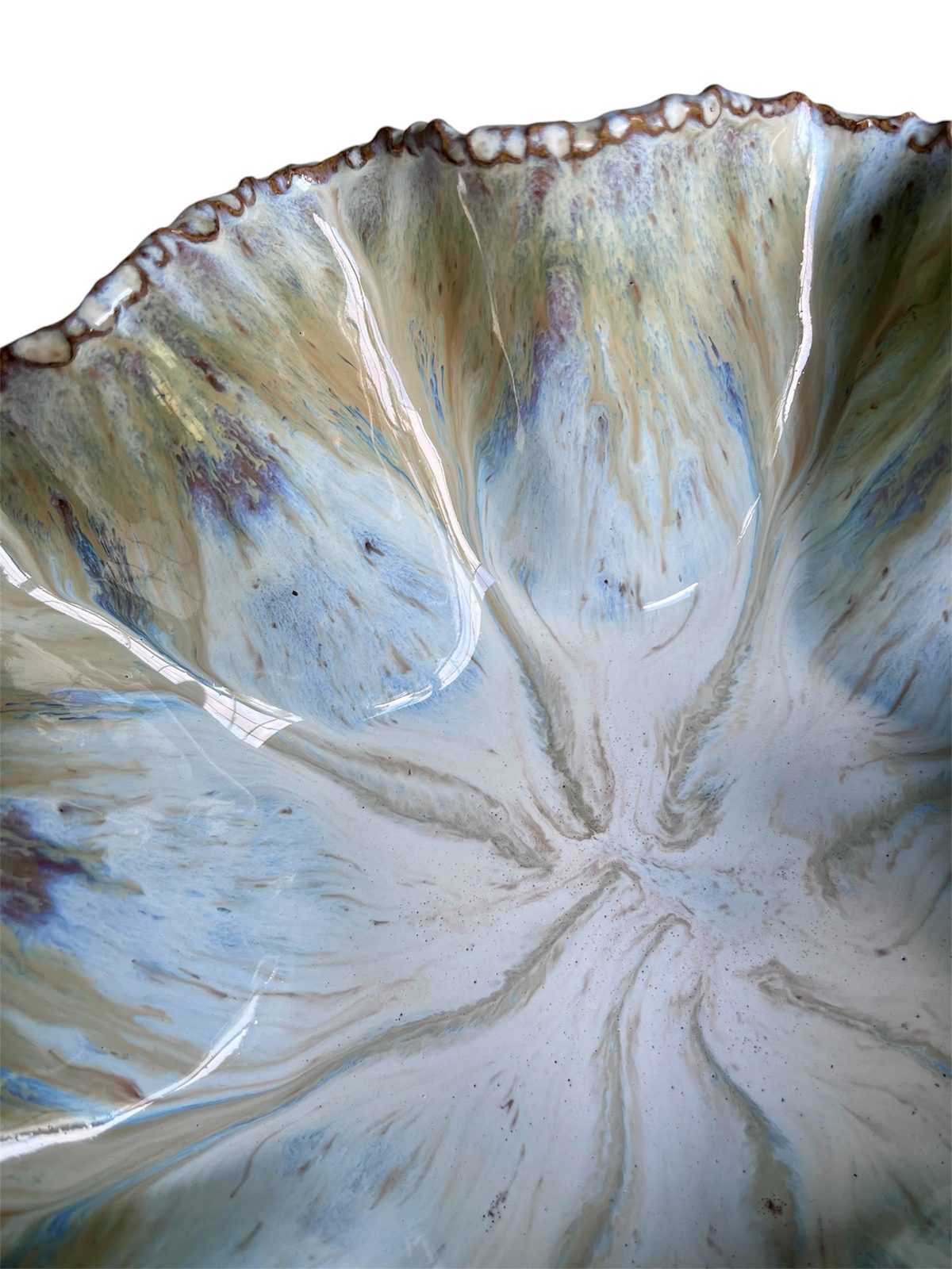 Close view of a flowing cream, blue and rust glaze breaking over a carved stoneware rim